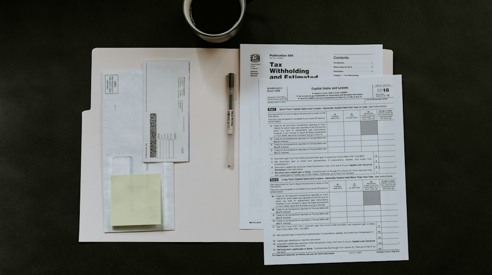 Tax forms, a pen and a coffee mug on a desk